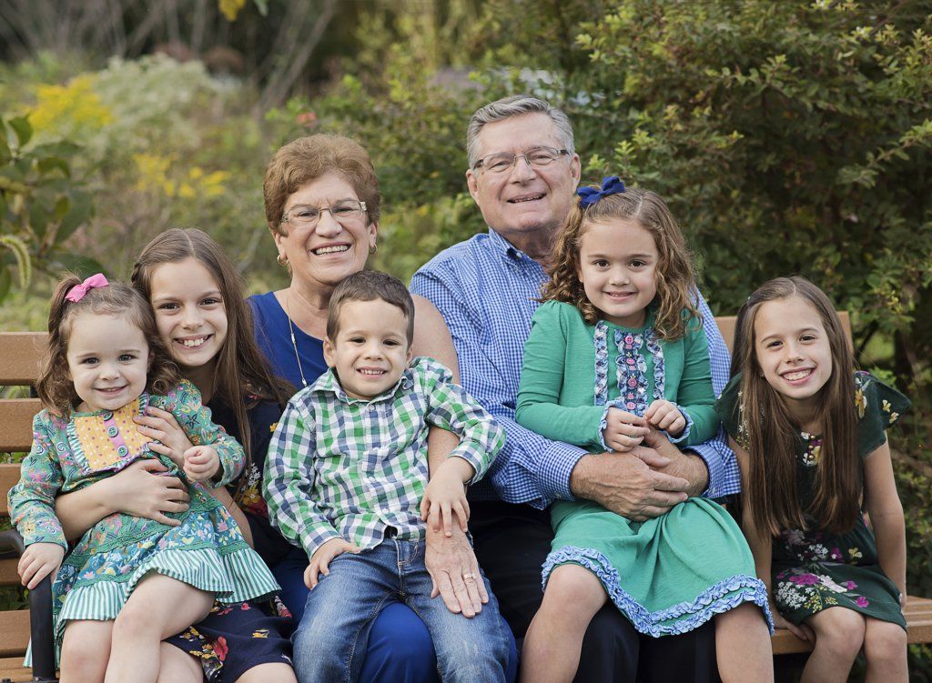 grandchildren sitting with grandparents on a bench at the park