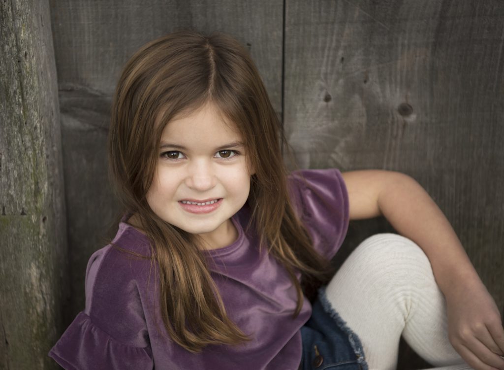 girl_sitting_on_ledge_in_front_of_barn_at_Heckler_Plains_Farmstead