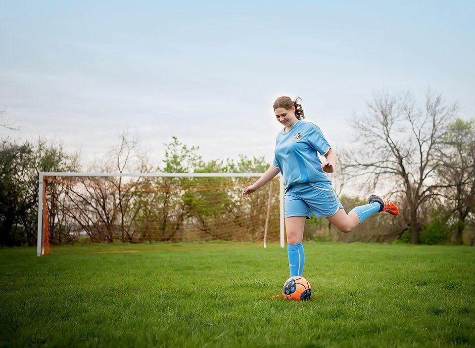 senior-portraits-girl-playing-soccer-field-blue-uniform-kicking-soccer-ball-lansdale-family-photographer