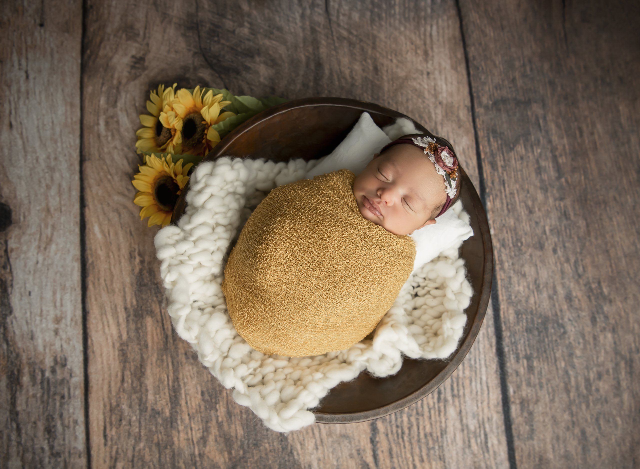 newborn baby girl sleeping in wood bowl in mustard wrap with sunflowers - Lansdale Family and Newborn Photographer
