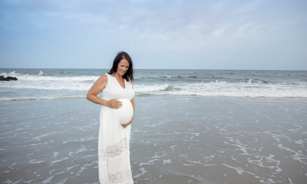materntiy portrait of mom holding her belly on the Ocean City NJ beach