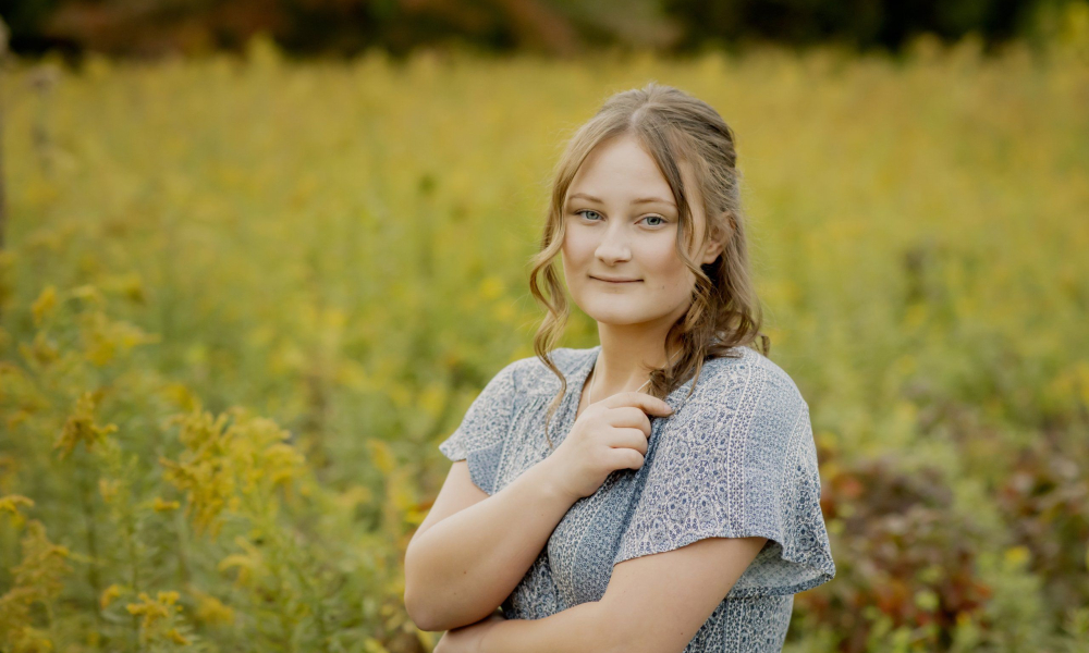 High school senior standing in a field of yellow flowers at Prophecy Creek Park at the Manor House in Ambler