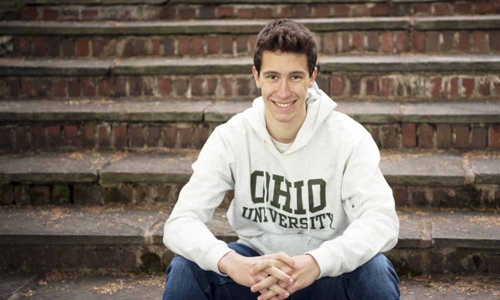 High School Senior sitting in brick steps wearing Ohio University shirt at Highland Mansions in Ft. Washington Lansdale family and newborn photographer