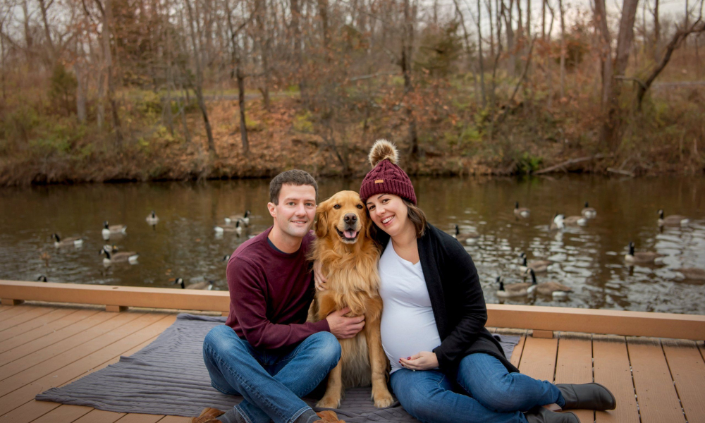 Husband and pregnant wife with their dog at fischers park in Lansdale sitting on the peer by the water with ducks