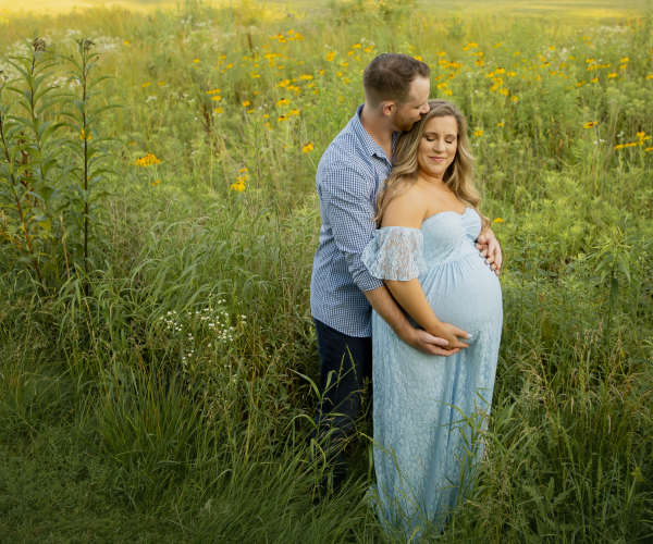 Husband kissing head of pregnant wife while holding hands at fischers park- Lansdale family and newborn photographer