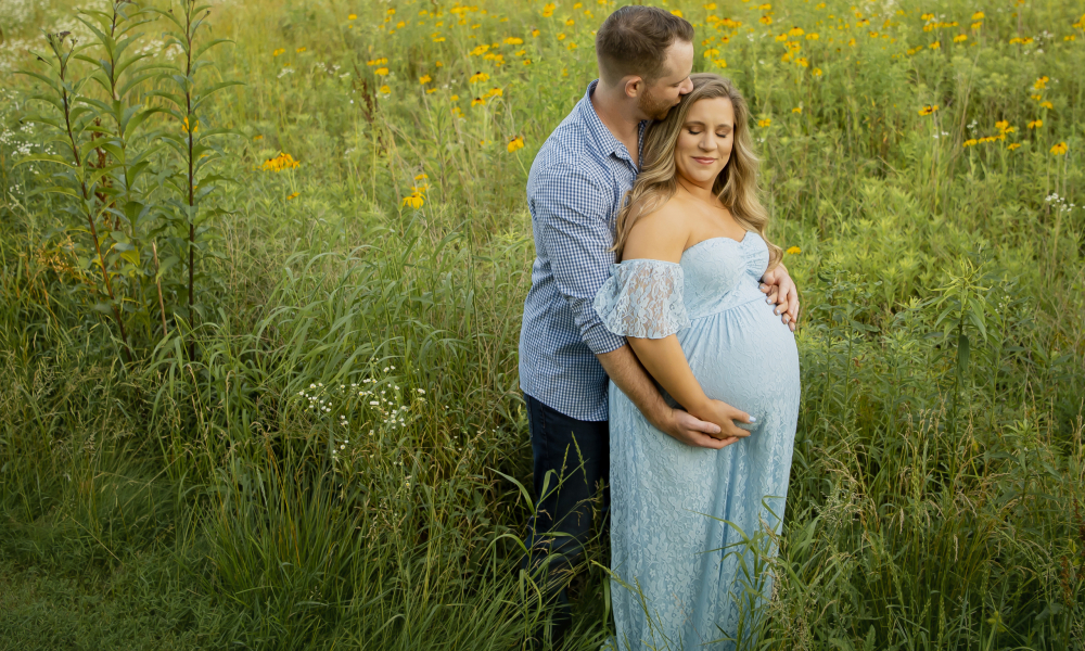 Husband kissing head of pregnant wife while holding hands at fischers park- Lansdale family and newborn photographer