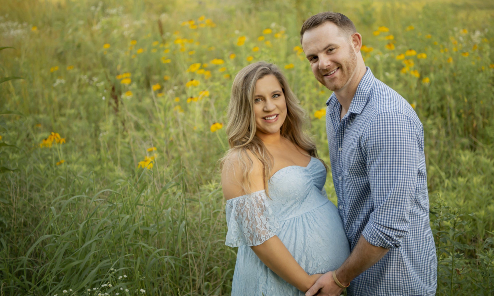 Husband holding hand his pregnant wife in the field