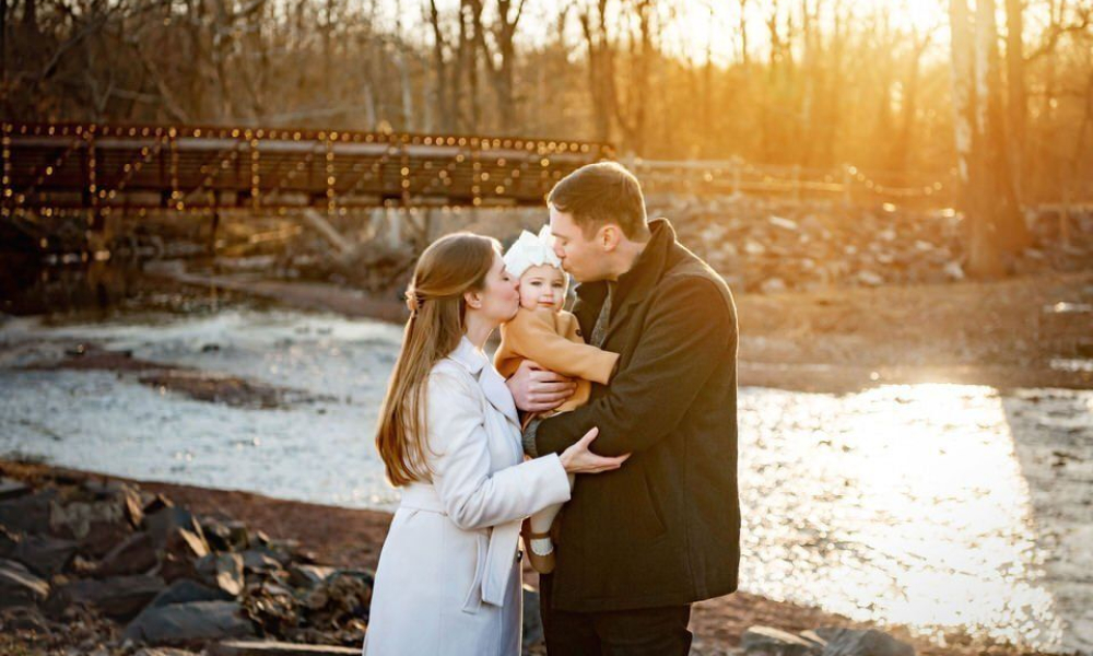 Mom and Dad kissing their daughter