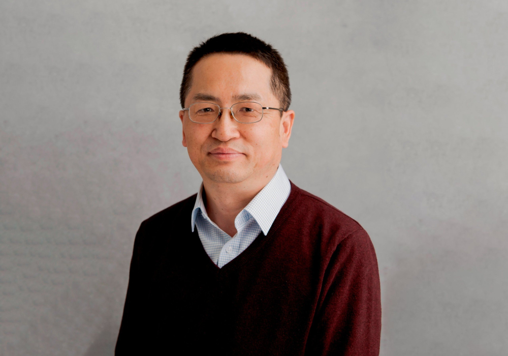 Professional headshot of A man in check shirt and red sweater Lansdale