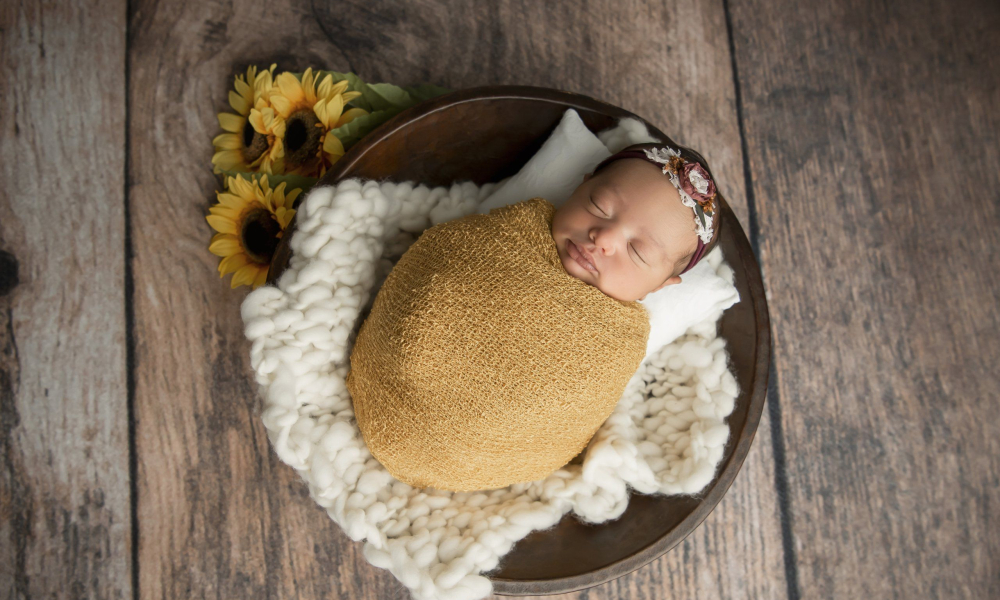 newborn baby girl sleeping in wood bowl in mustard wrap with sunflowers - Lansdale Family and Newborn Photographer