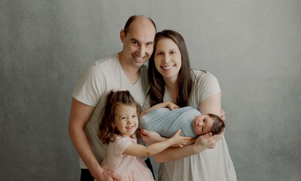 Little girl holding a baby with her parents
