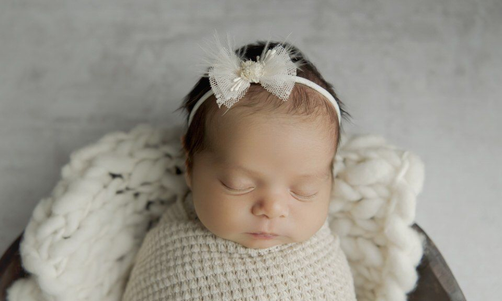 Newborn in white wrap and white hairband