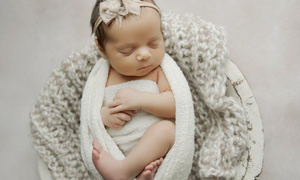 Newborn in white wrap with hairband