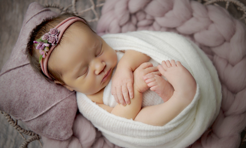 Newborn baby sleeping on light purple pillow