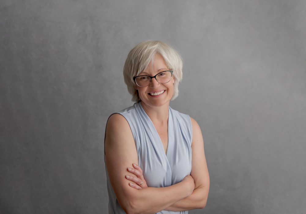 A women wearing glasses and showing her teeth while smiling